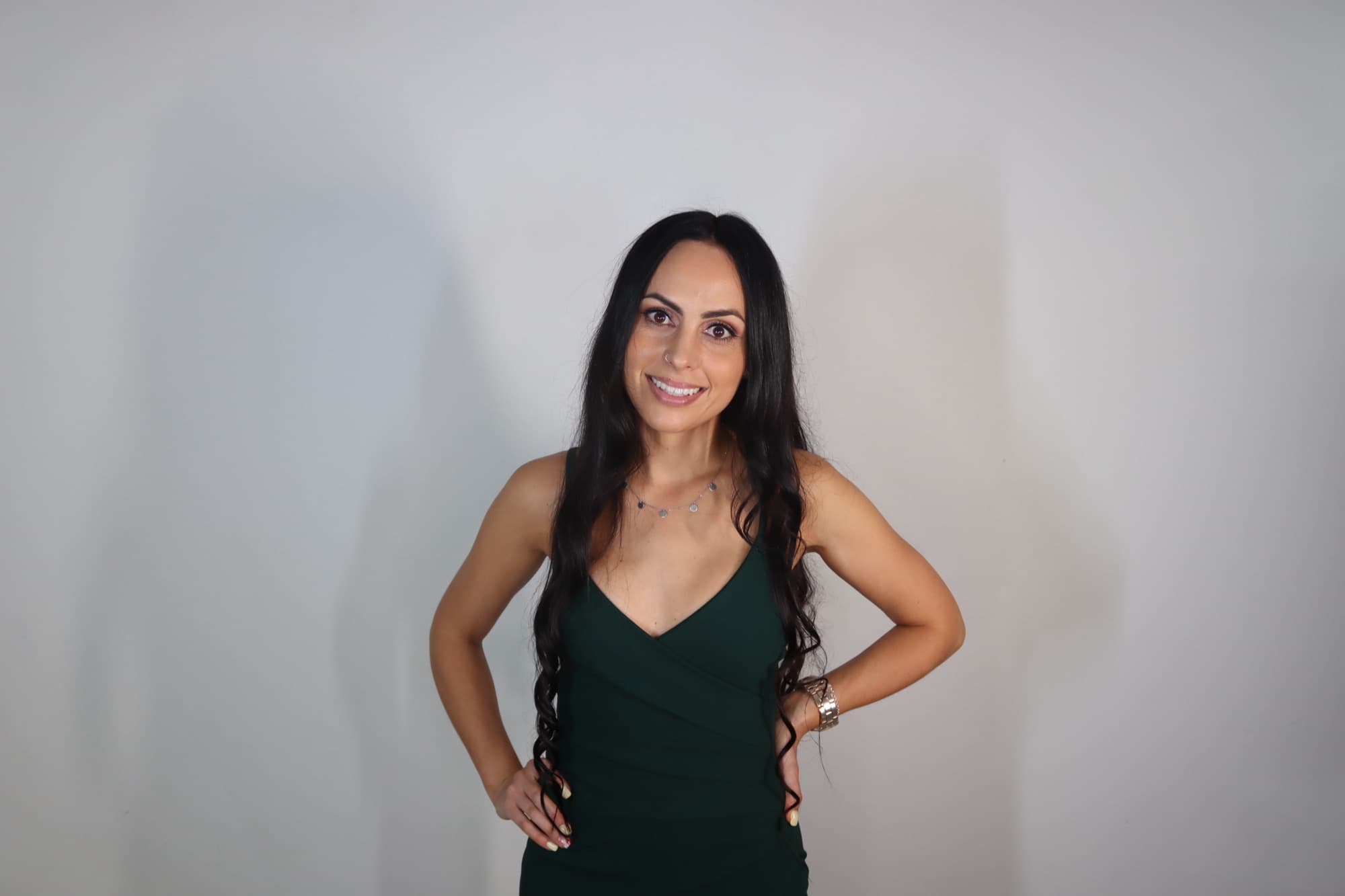 A single still photo of a guest in a green dress against a plain studio wall