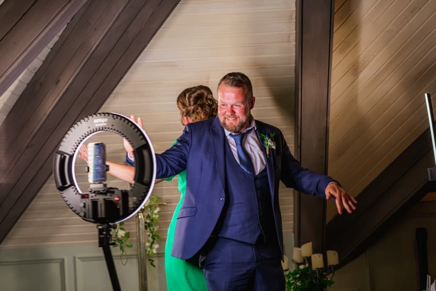 Guest with arms outstretched being filmed by a 360 video booth at a wedding reception