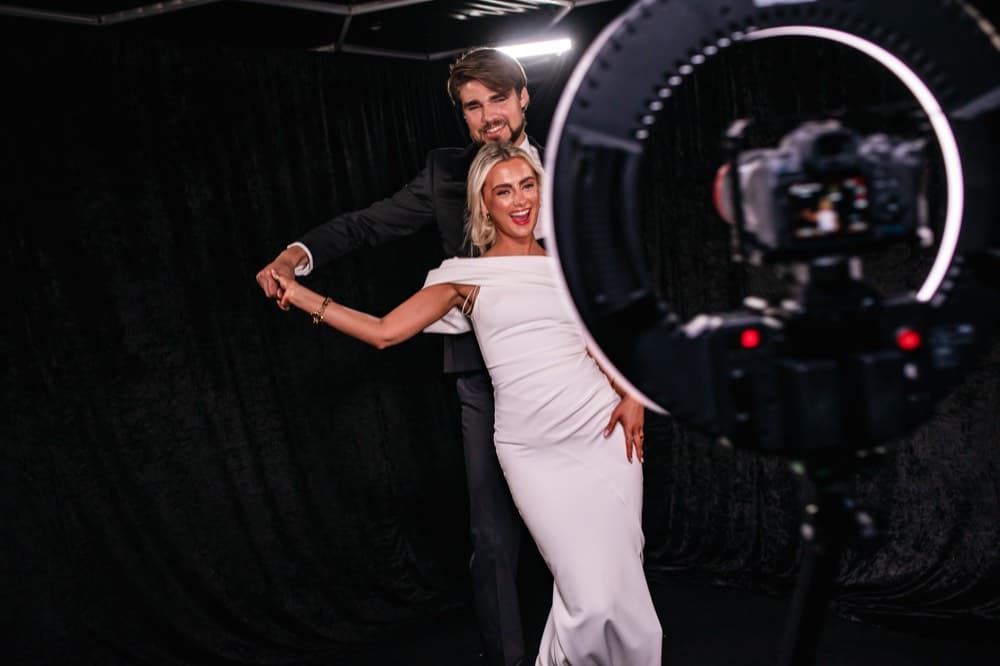 Couple posing for a ring-light photo booth camera at a wedding reception