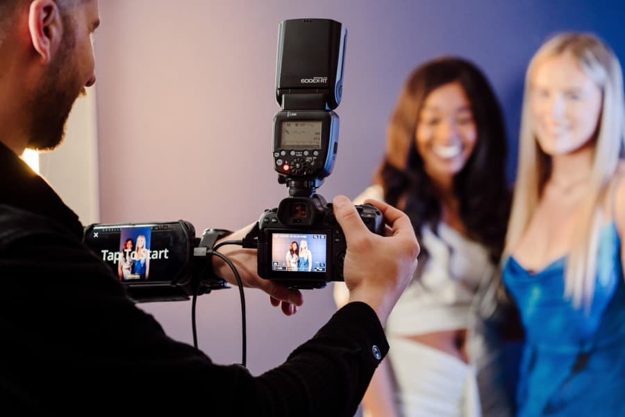 Photographer using a tethered camera with an iPad attached to capture two guests away from a fixed booth